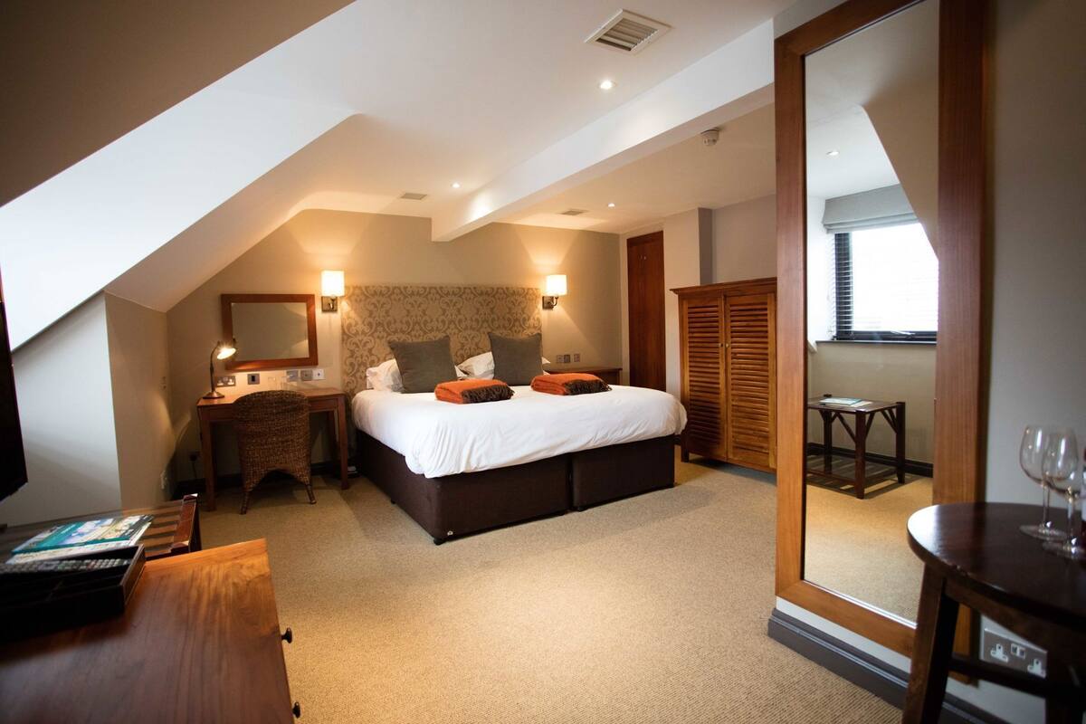 Une chambre à coucher comprenant un lit, une table de chevet, une lampe, une armoire et un bureau avec une chaise.