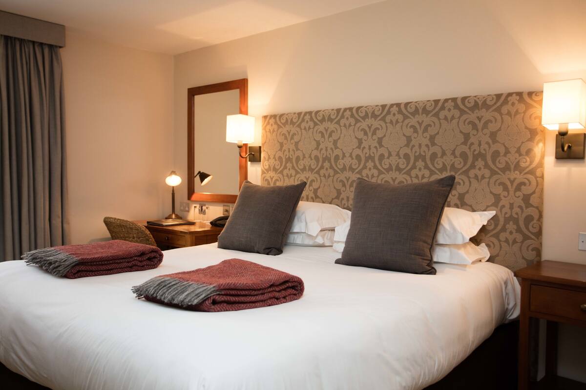 Une chambre d’hôtel avec un grand lit, deux lampes de chevet, une table de chevet et un miroir.