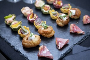 A slate serving board with various appetizers, including some with meat and cheese, arranged neatly.