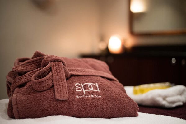 A brown towel with the spa logo and name, placed on a white surface.