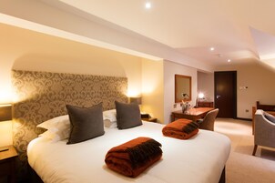 Una habitación de hotel con una cama grande, dos mesitas de noche con lámparas, un escritorio con una silla y un espejo en la pared.