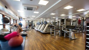 A gym with exercise equipment, wooden flooring, and a TV screen. - Barnham Broom Hotel, Golf & Spa (Norwich)