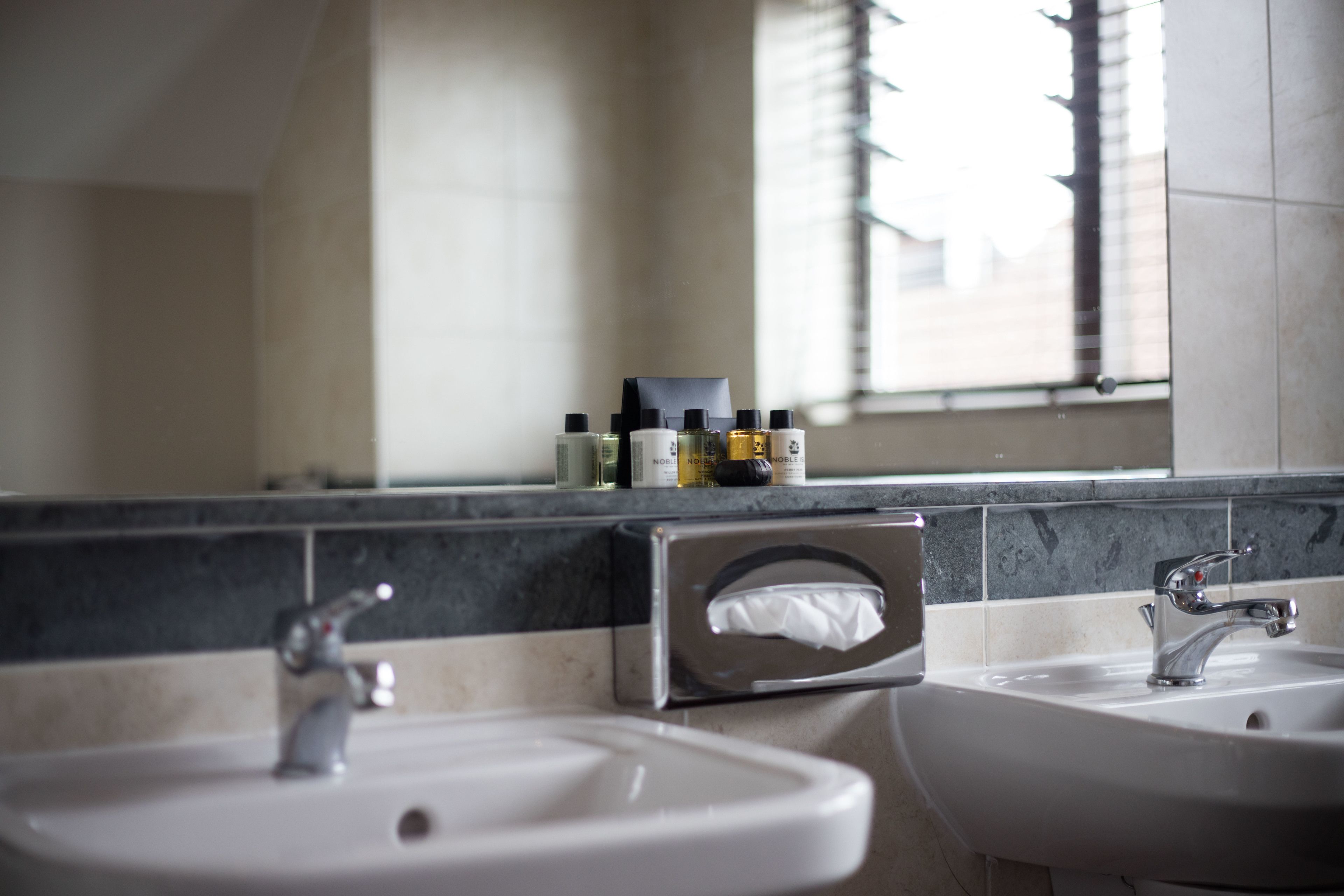 A bathroom with two sinks, a mirror, and a window.
