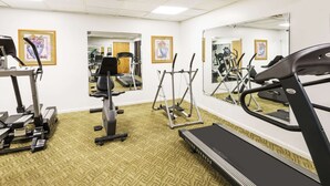Un gimnasio con cintas de correr, elípticas y equipo de pesas.