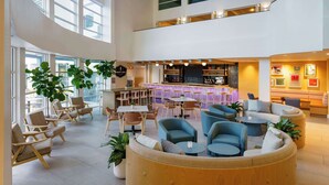 A spacious lobby with a bar area, seating arrangements, and large windows allowing natural light. - Hilton Garden Inn Dana Point Doheny Beach (Dana Point)