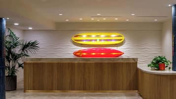 A reception area with a wooden reception desk, a potted plant, and a wall with a wavy texture.