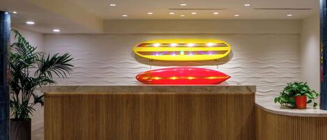 A reception area with a wooden reception desk, a potted plant, and a wall with a wavy texture.