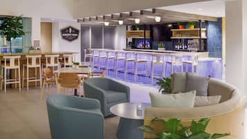 A modern bar area with a bar counter, seating, and a sign for 'Doheny Surf Restaurant'.