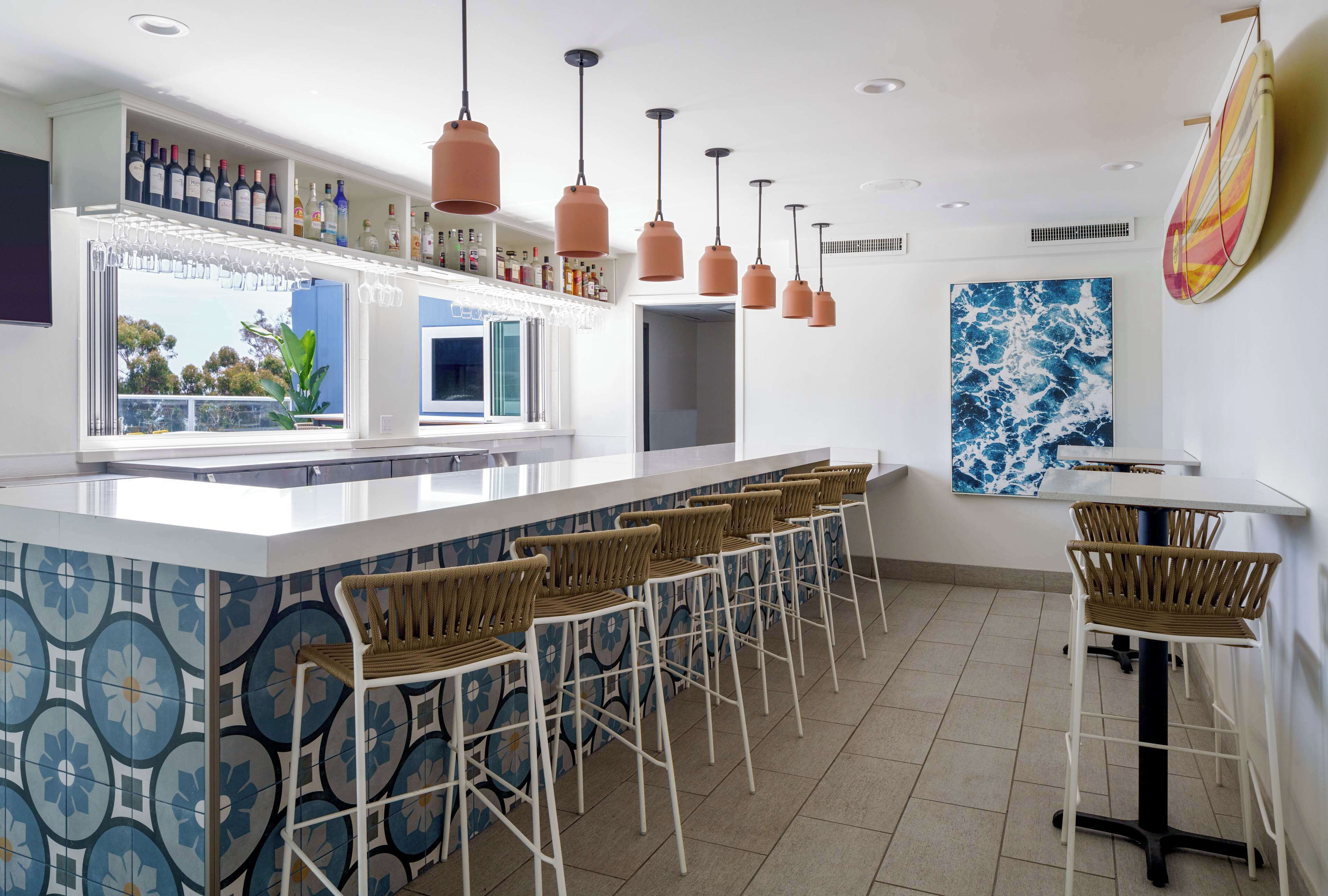 A bar area with a long counter, multiple hanging pendant lights, and bar stools.