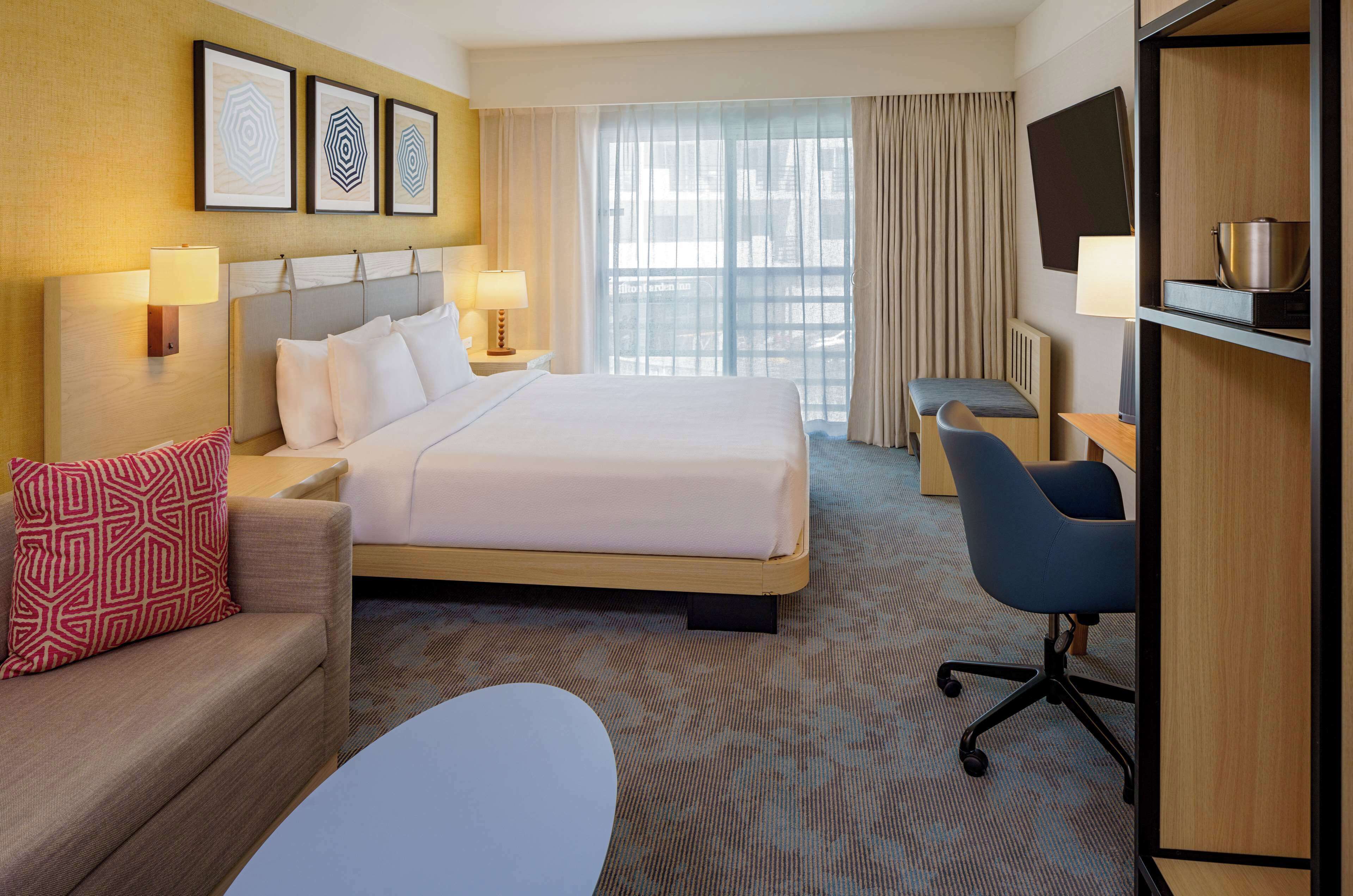 Ein Hotelzimmer mit Bett, Schreibtisch, Stuhl und Fernseher.
