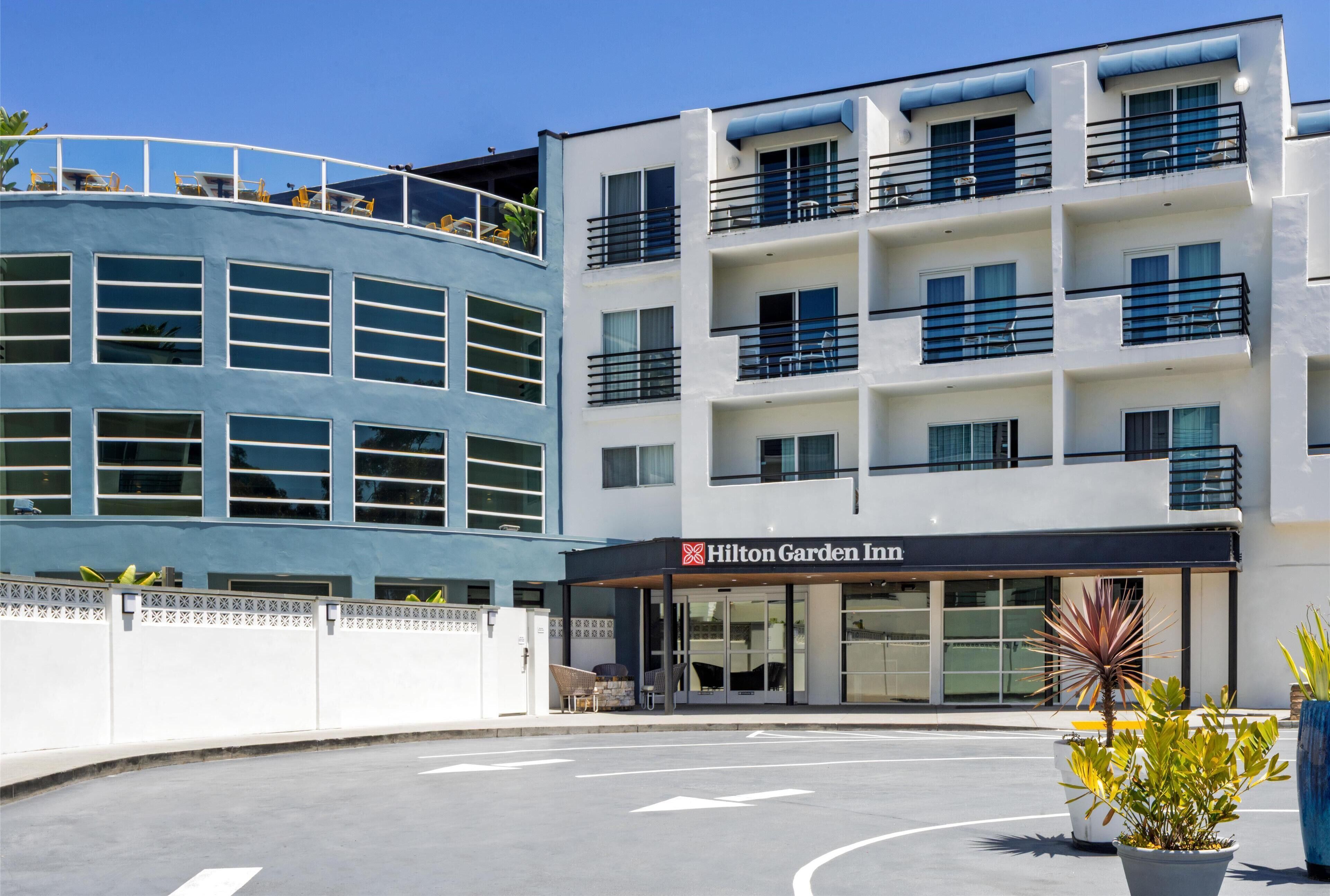 A modern hotel with a curved facade, multiple balconies, and a clear sky.