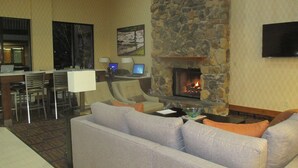 A cozy living area with a stone fireplace, comfortable seating, and a dining area with a bar.