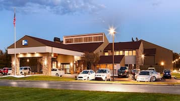 Welcome to our hotel, featuring a prominent entrance and a well-lit facade with a flat roof and large windows.