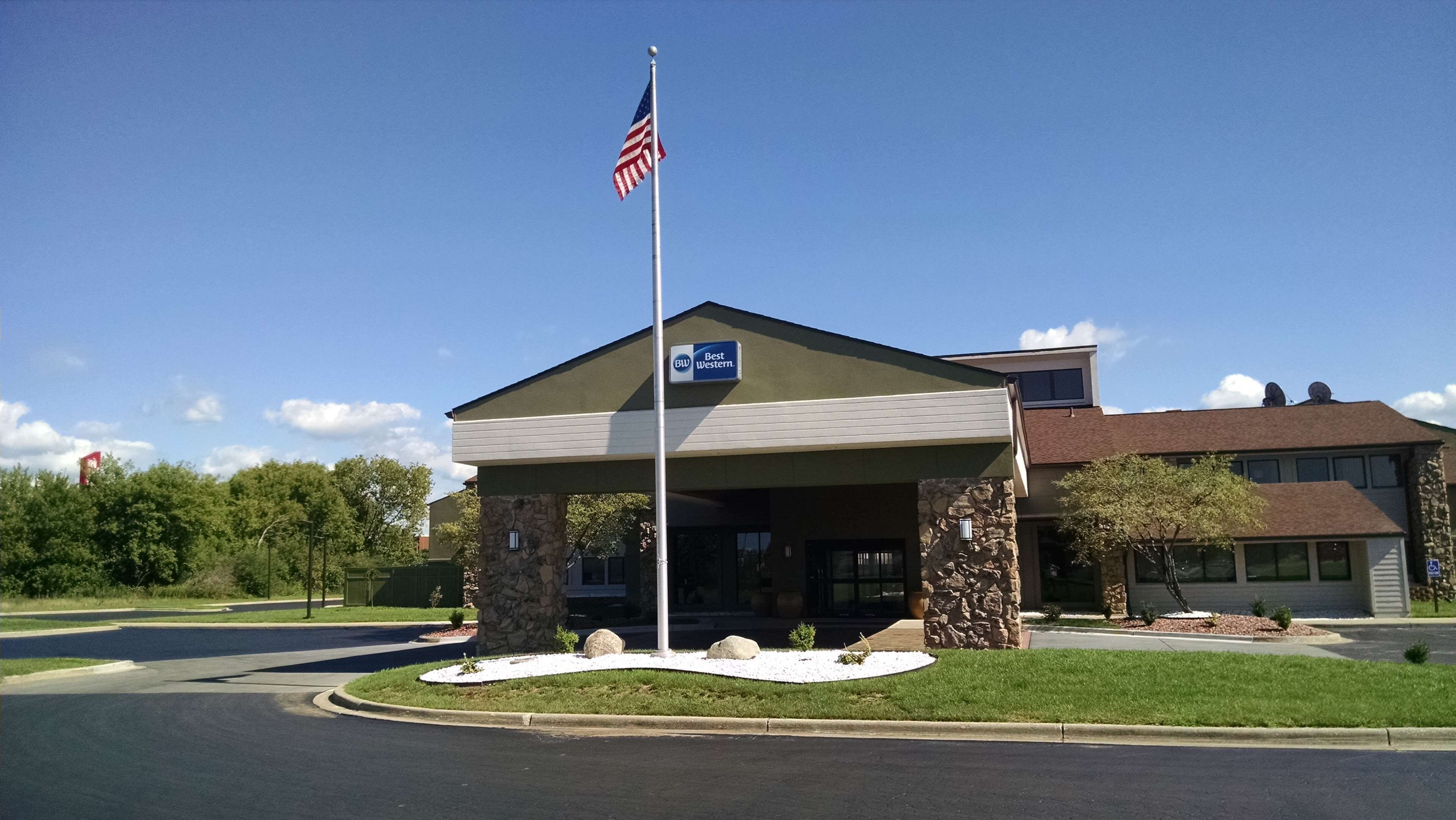 A hotel with a stone facade, a covered entrance, and an American flag.