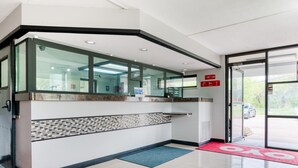 A reception area with a glass counter, tiled floor, and a red mat leading to the entrance. - Dallas Love Field Inn (Dallas)