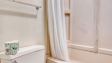 A bathroom with a toilet, a shower curtain, and a towel hanging on the wall.