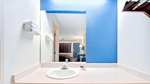 A hotel bathroom with a white sink, a mirror, and a blue accent wall. - Dallas Love Field Inn (Dallas)