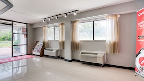 A spacious lobby with a tiled floor, air conditioning units, and large windows with curtains. - Dallas Love Field Inn (Dallas)