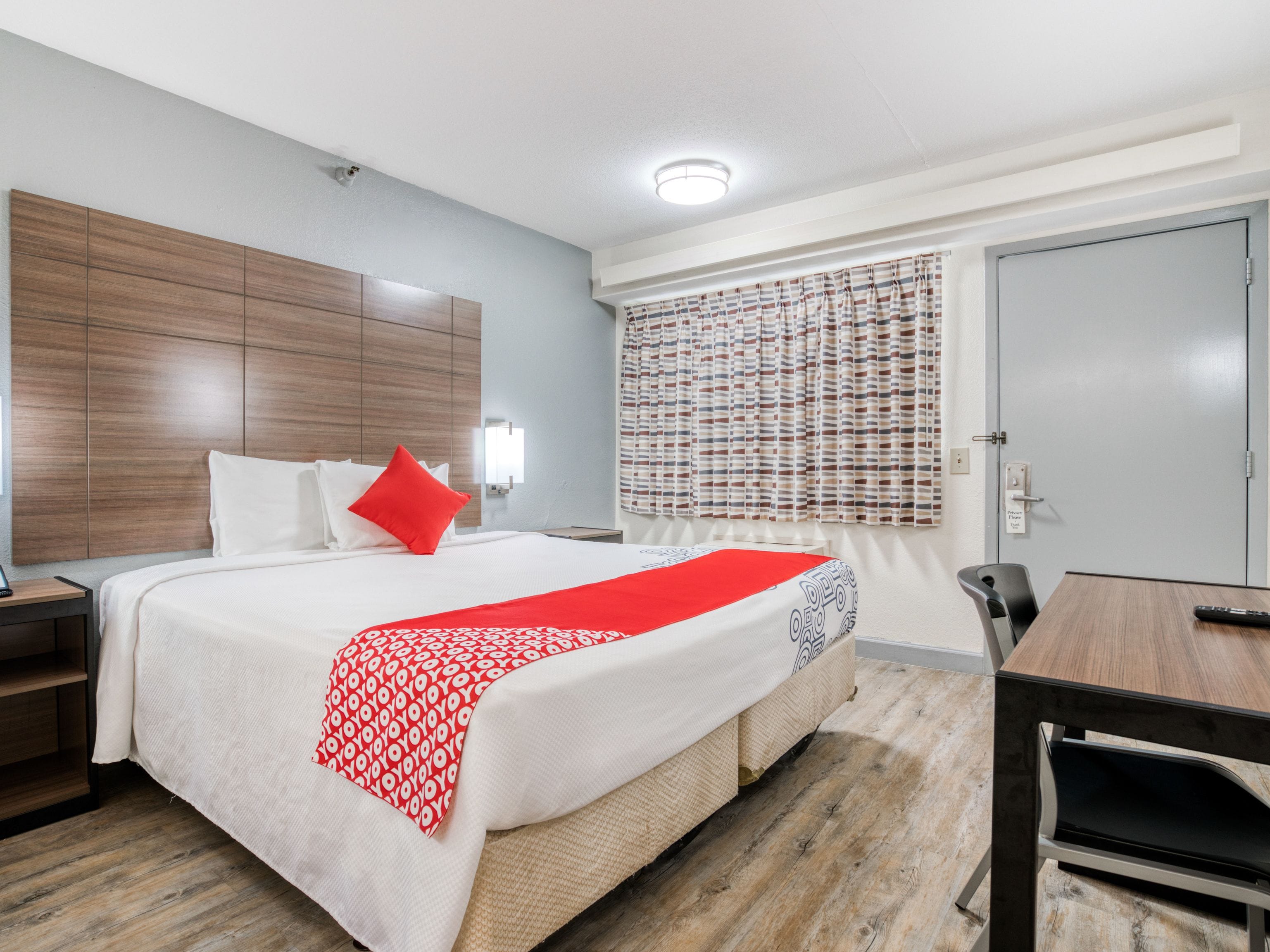 A hotel room with a large bed, a bedside table, a desk, and a chair.