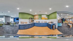 A modern kitchen with blue cabinets, a wooden countertop, and a curved island. - Spark by Hilton Moline Quad Cities (Moline)