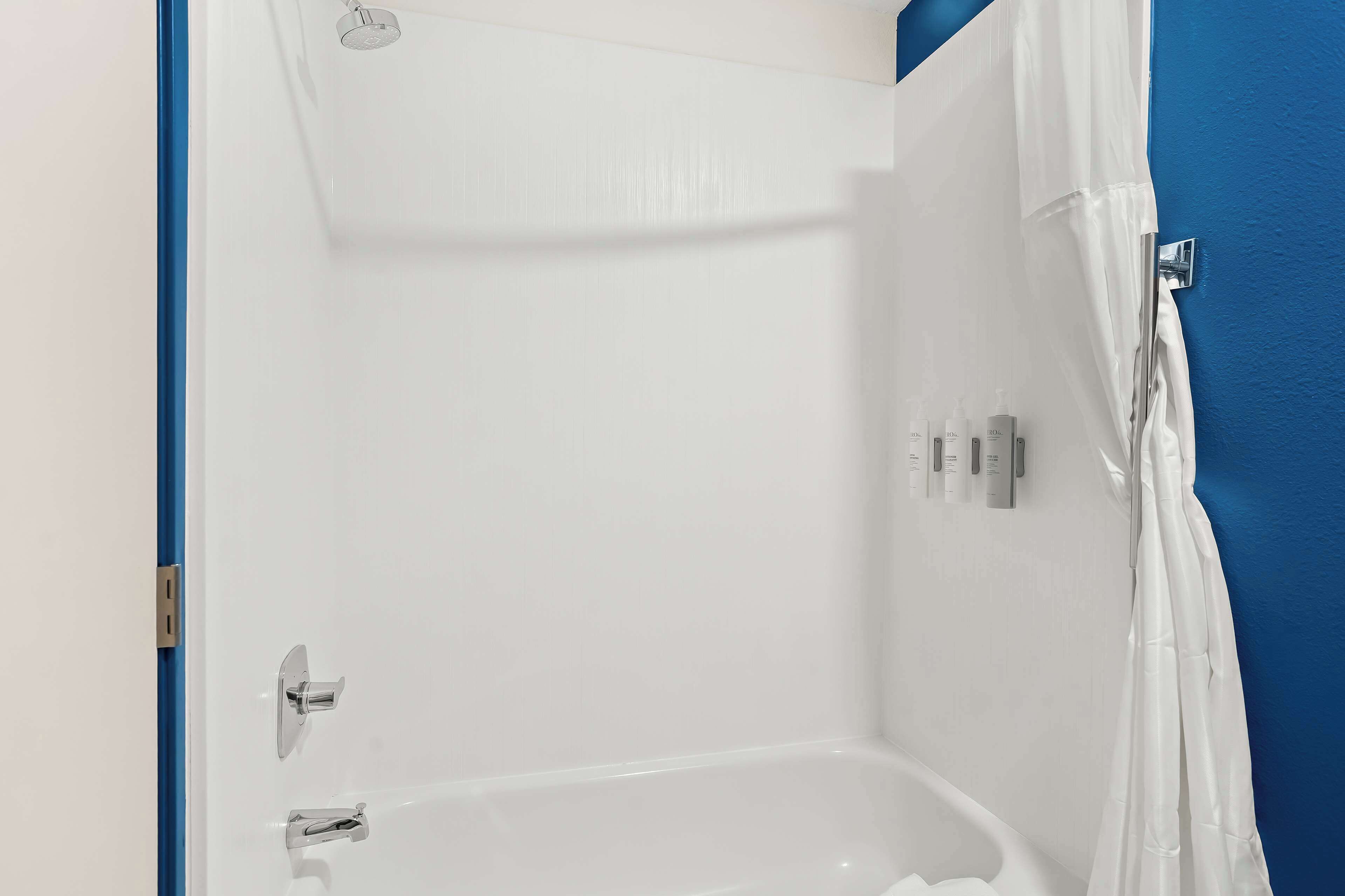 A bathroom with a bathtub, a shower curtain, and a wall-mounted towel rack.
