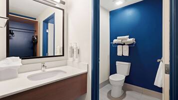 A modern bathroom with a white sink, mirror, and a blue accent wall.