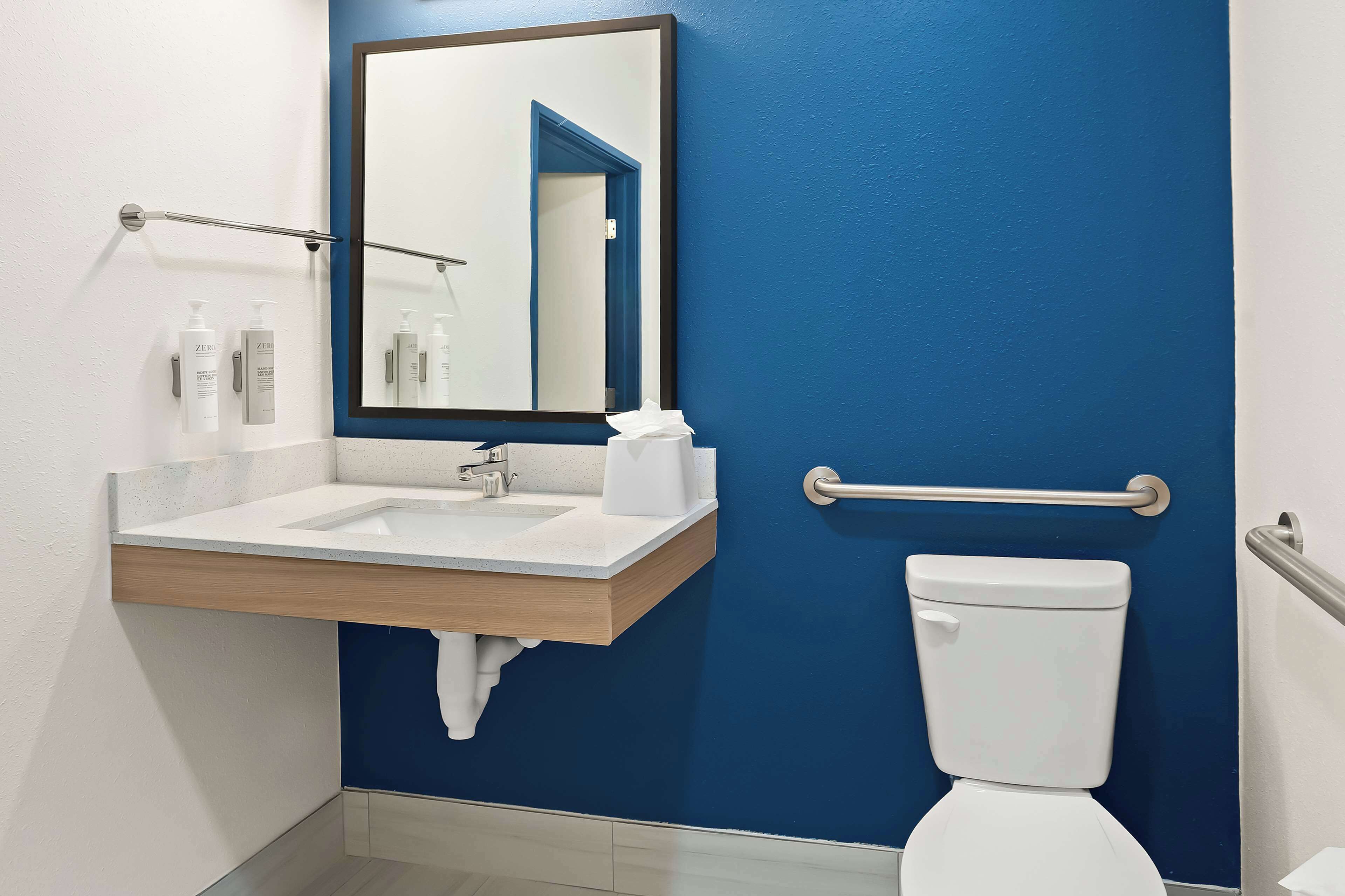 Een moderne badkamer met een blauwe wand, een witte wastafel en een toilet.