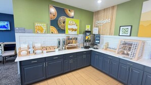 A breakfast area with a coffee machine, yogurt dispenser, and various food items. - Spark by Hilton Moline Quad Cities (Moline)