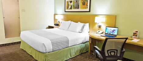 Une chambre d’hôtel équipée d’un lit, d’un bureau, d’une chaise et d’un ordinateur portable.