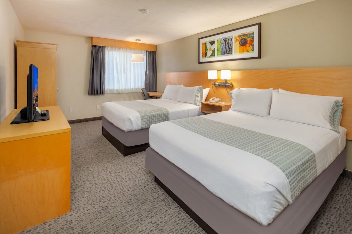 Ett hotellrum med två sängar, ett skrivbord, en telefon och en tavla på väggen.