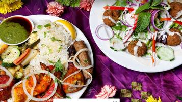 A table with two plates of food, one with rice and vegetables, and the other with a salad and meatballs.