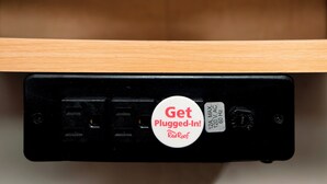 A black electronic device with a white sticker that reads 'Get Plugged-In! RedRoof.' - Red Roof Inn Detroit - Dearborn/Greenfield Village (Dearborn)