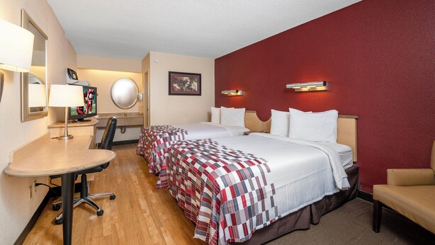 A hotel room with two beds, a desk, a chair, a TV, and a mirror. - Red Roof Inn Detroit - Dearborn/Greenfield Village (Dearborn)