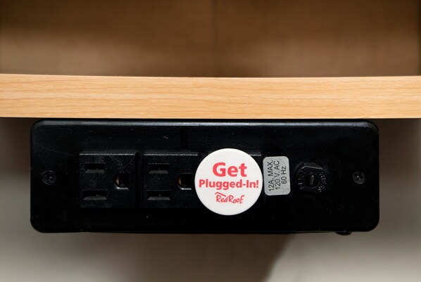 A black electrical outlet with a white plug-in button labeled "Get Plugged-In! RedRoof."