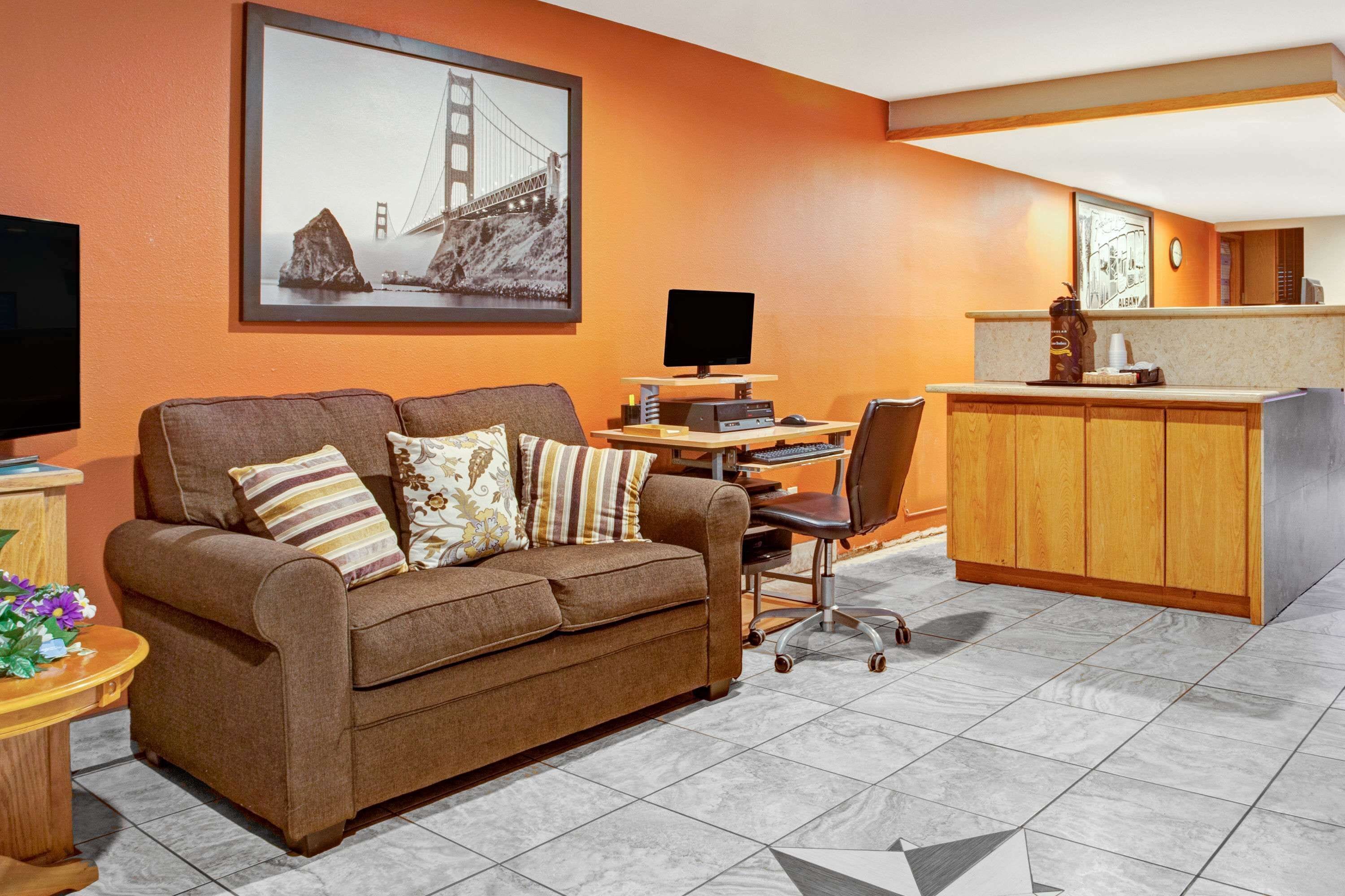 A living room with a brown sofa, a coffee table, a TV, and a desk with a computer.