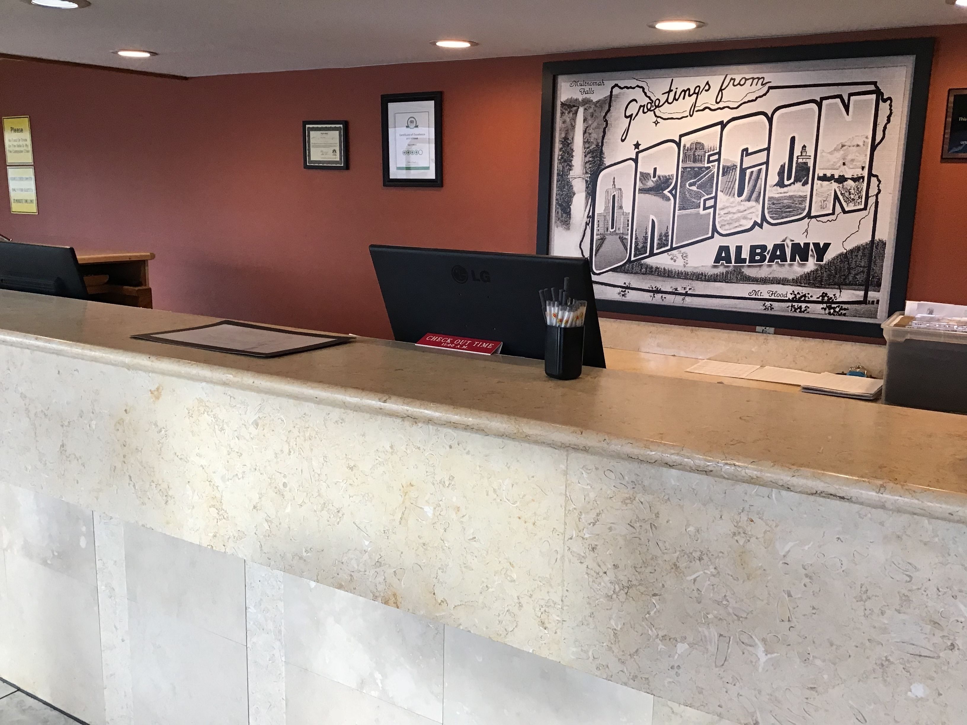A reception desk with a framed welcome sign, a laptop, and a pen holder.