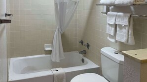 Un baño con bañera, inodoro y cortina de ducha.