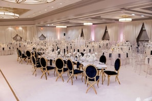 Une salle de banquet avec des tables rondes, des chaises et des lustres.
