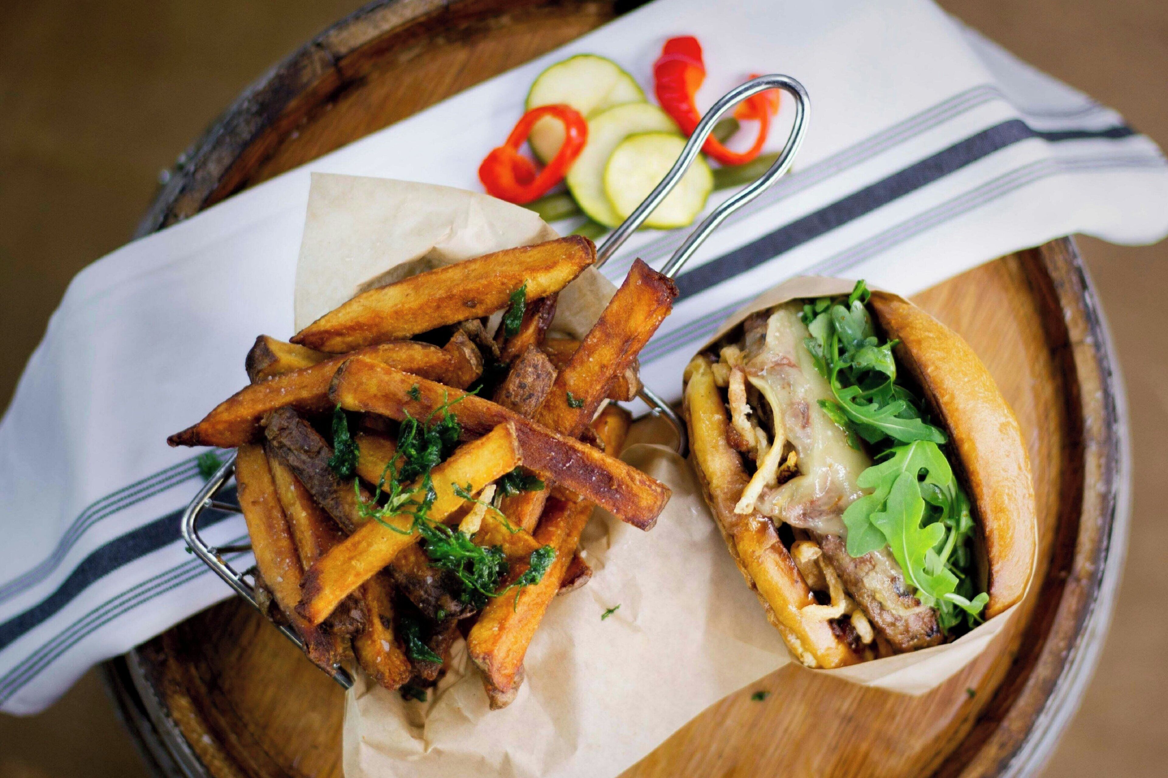 A meal consisting of fries and a sandwich on a wooden tray.