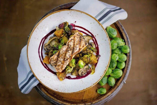 A plate of food with Brussels sprouts and a piece of grilled meat, served on a white plate with a red sauce.