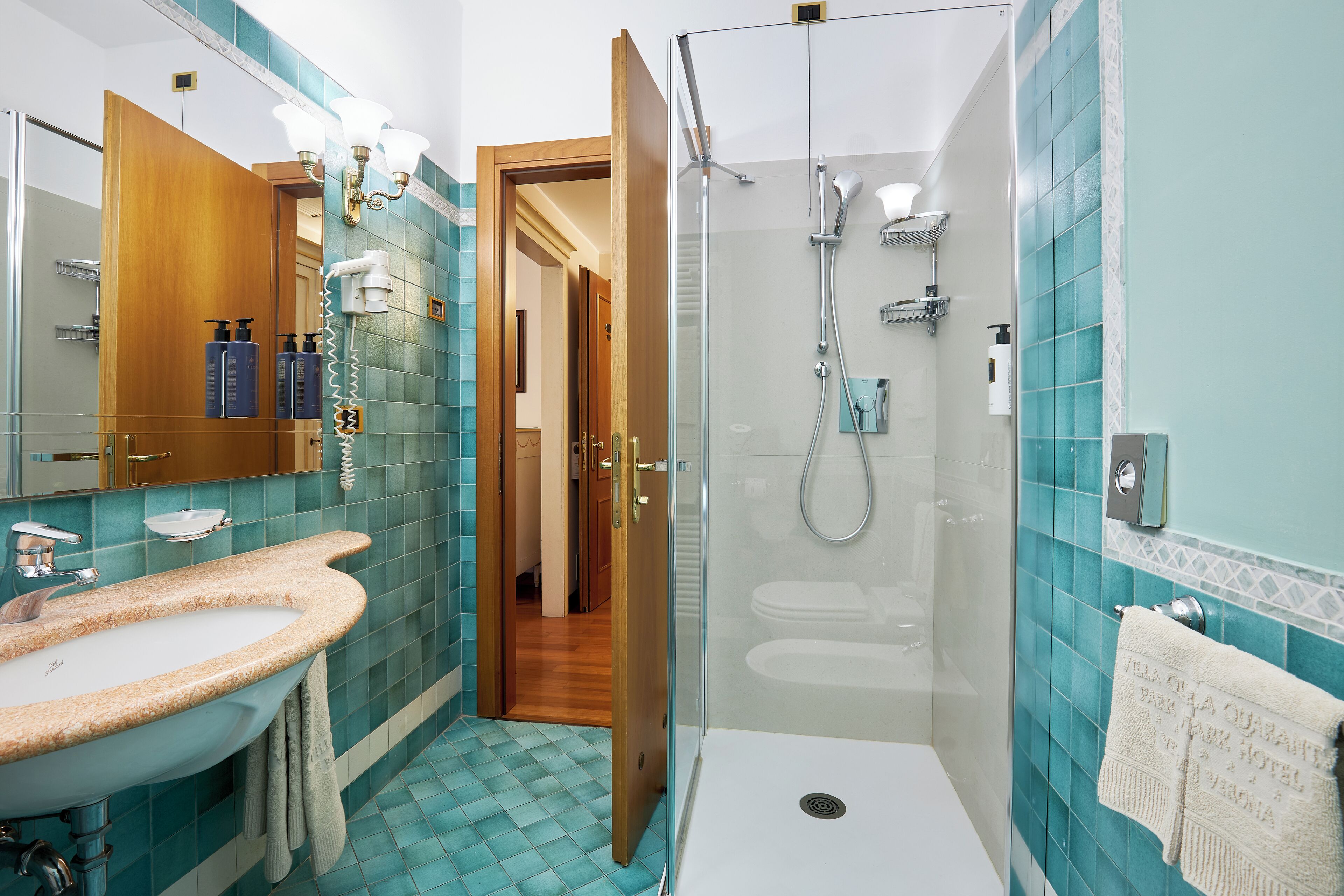 Ein Badezimmer mit Waschbecken, Spiegel, Dusche und gefliesten Wänden.