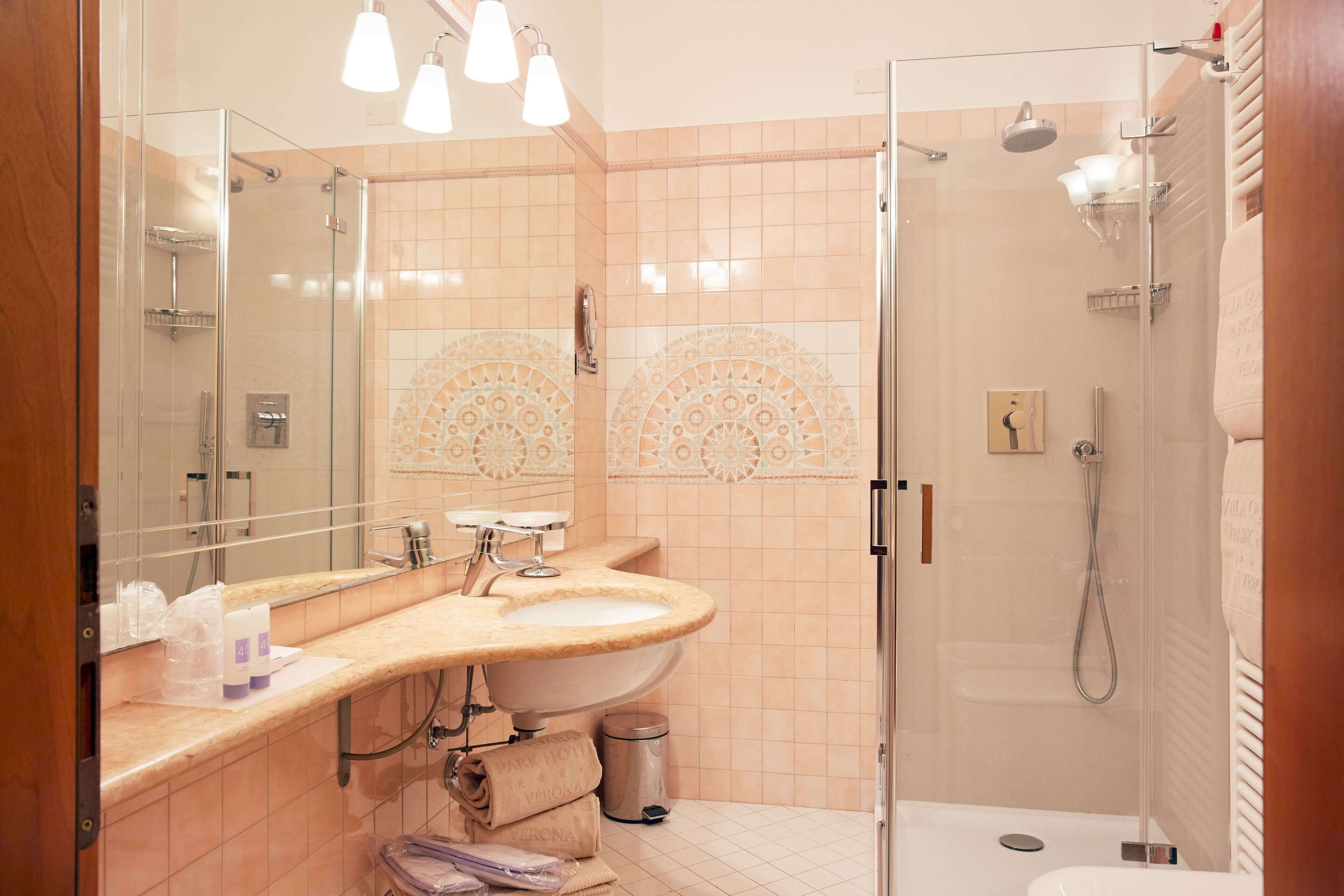 A modern bathroom with a glass-enclosed shower, a large vanity with a sink, and a mirror.