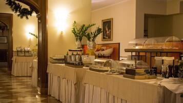 Un buffet proposant une variété de plats et de boissons, notamment un saladier de fruits et un distributeur de boissons.