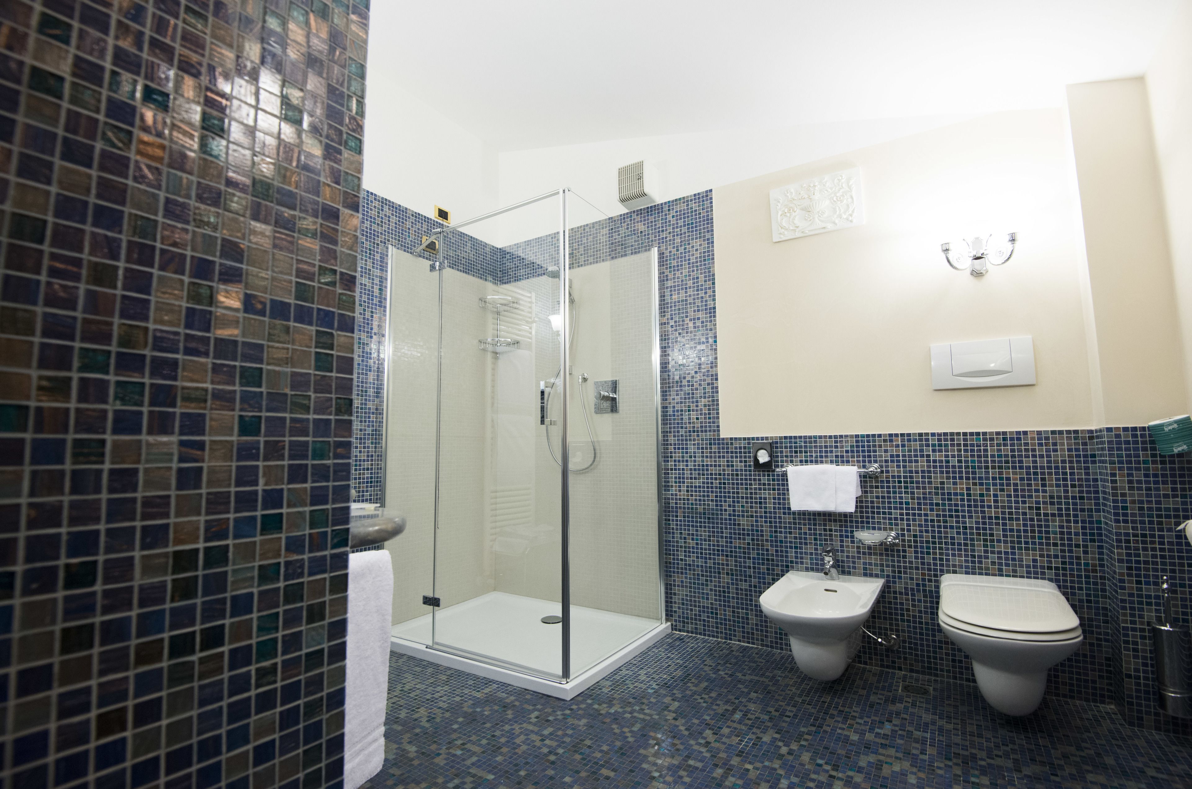 A bathroom with a glass-enclosed shower, a bidet, and a toilet.