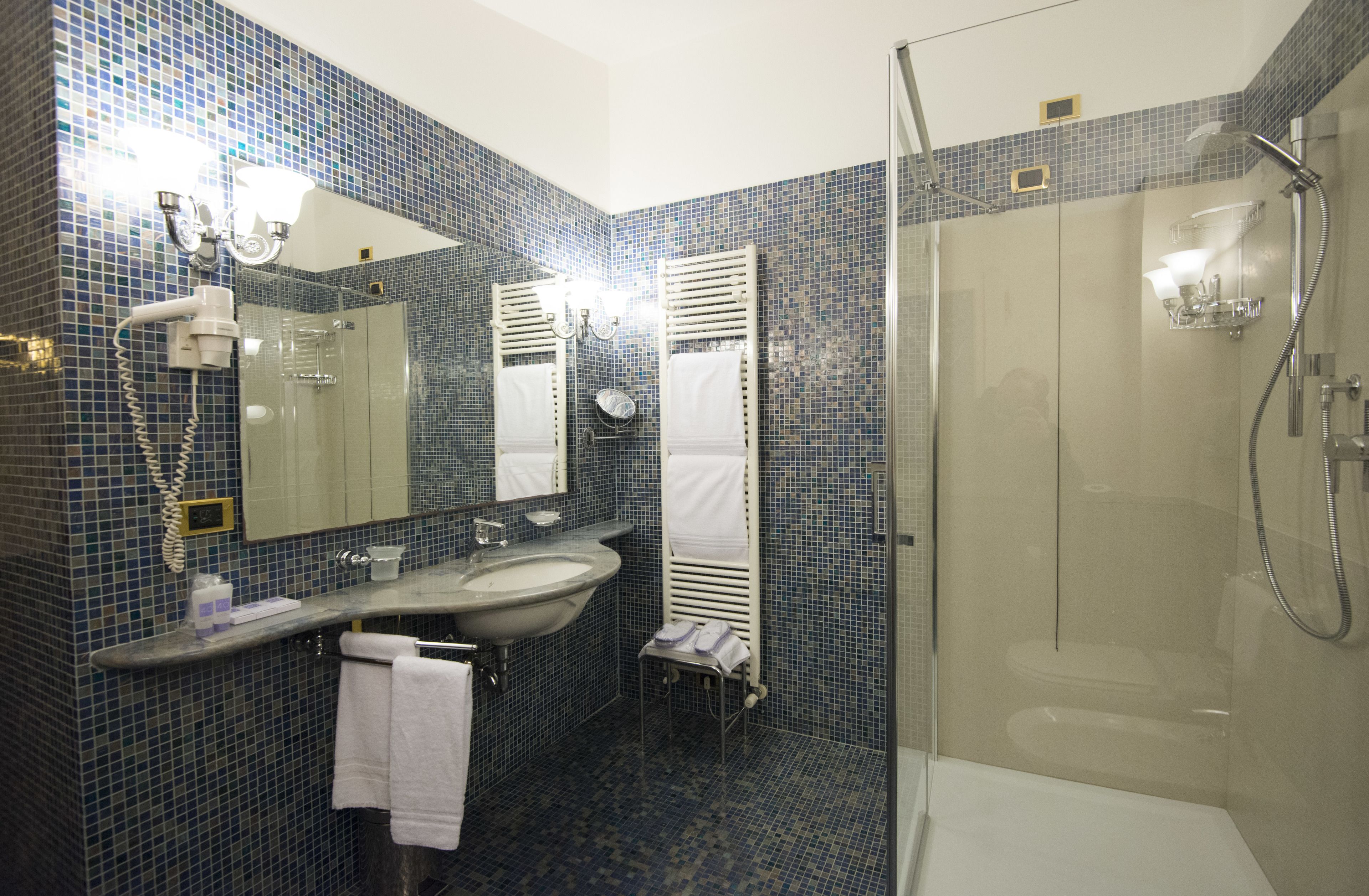 A bathroom with a glass-enclosed shower, a sink, and a mirror.