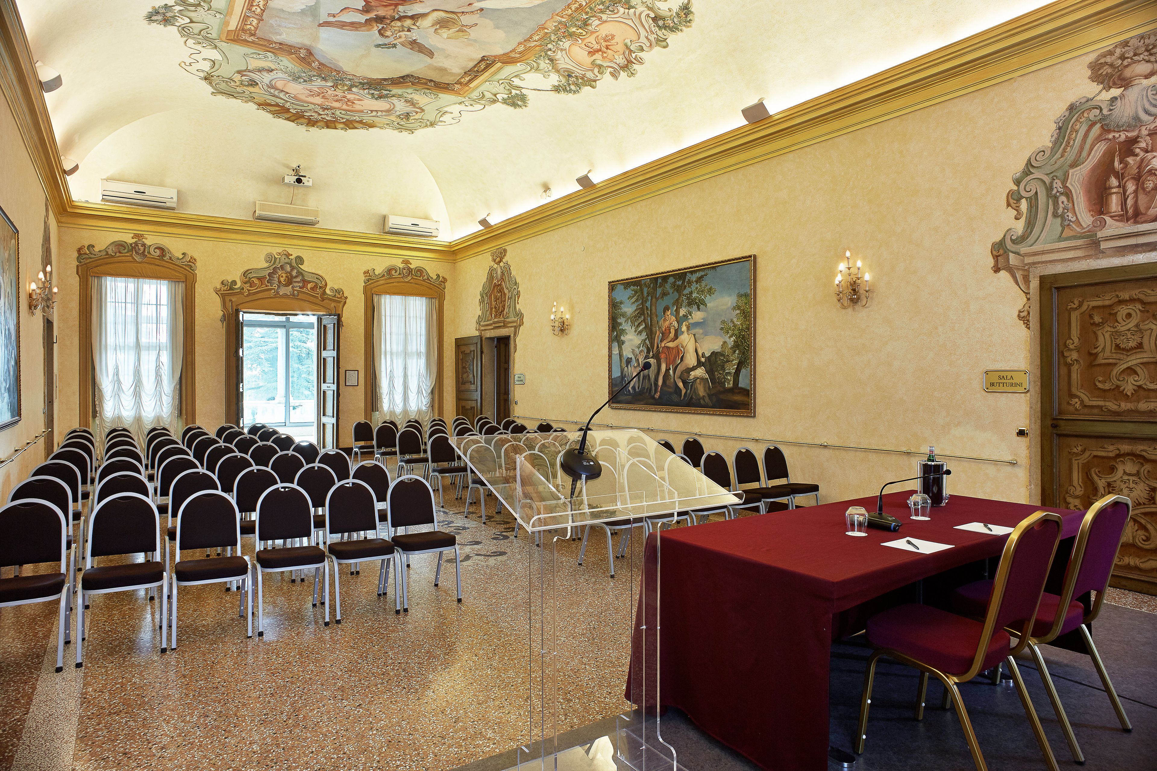 A conference room with rows of chairs, a table with a red tablecloth, and a microphone.