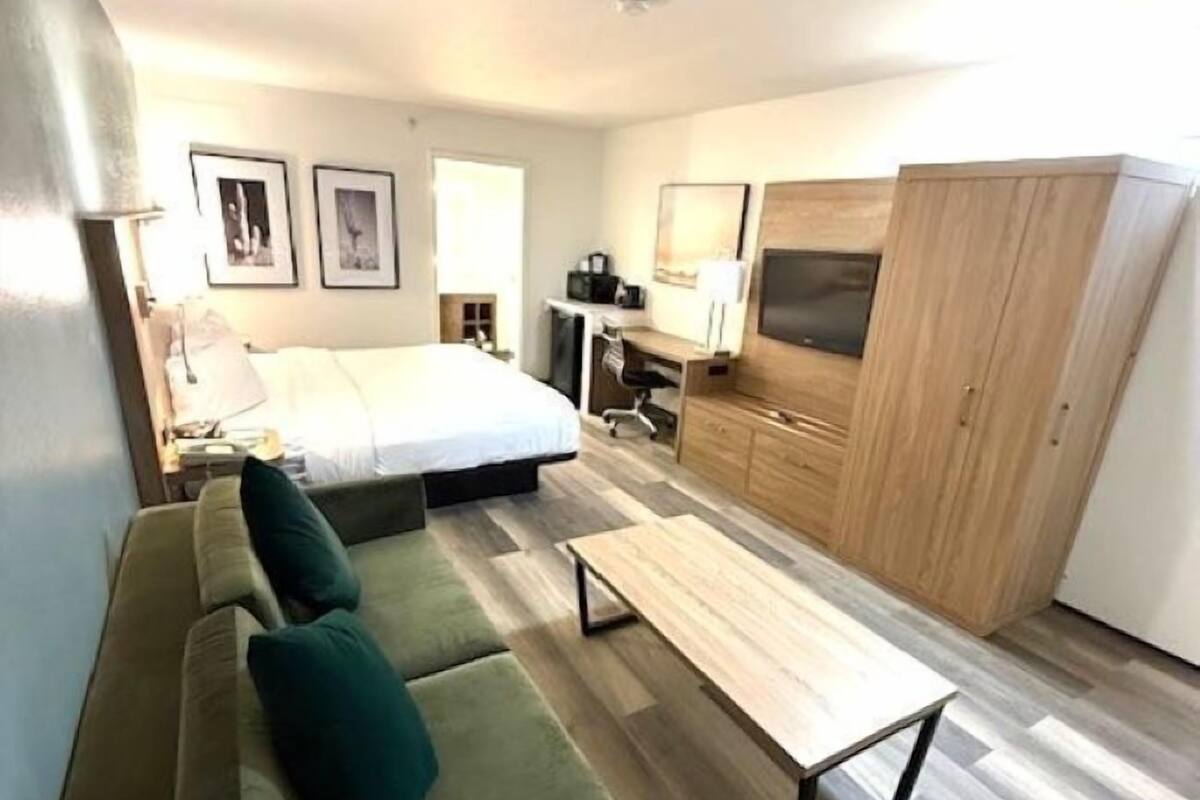 Una habitación compacta con cama, sofá, escritorio y armario.