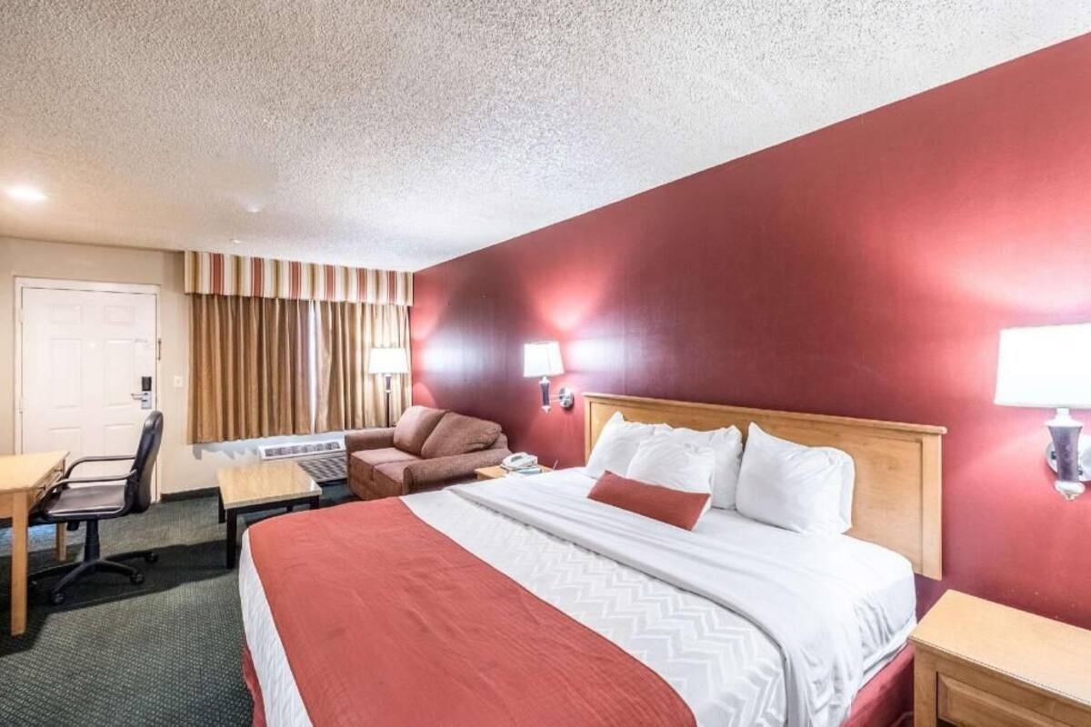 Una habitación de hotel con cama, escritorio, silla y lámpara.