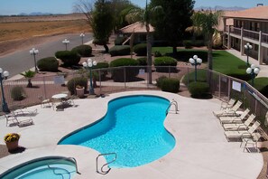 A swimming pool with a curved edge, surrounded by a fence, and equipped with lounge chairs and a table.