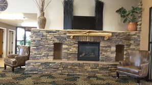 A stone fireplace with a flat-screen TV above it, flanked by two leather armchairs. - Inn at the Canyons (Monticello)